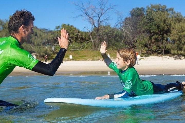 a young man riding a surfboard in the water